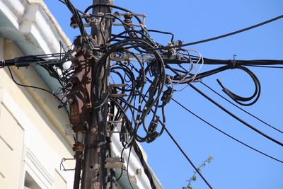 Low angle view of electricity pylon against clear blue sky