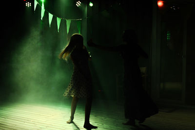 Rear view of women standing at night