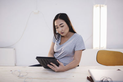 Female blogger using digital tablet at desk in office