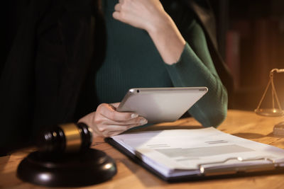 Midsection of woman reading book on table