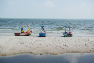 Boats moored on beach against sky