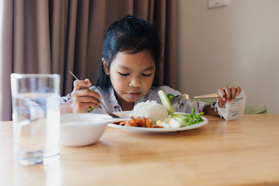 Side view of girl eating food at home