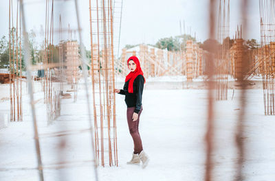Portrait of beautiful young woman standing at construction site during winter