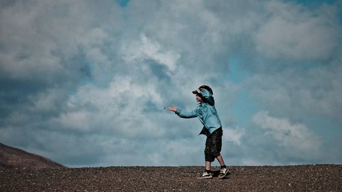 Woman jumping in park against cloudy sky