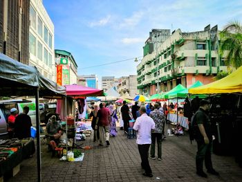 People on street market in city against sky
