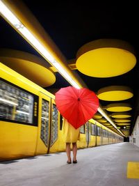 Woman with umbrella standing at railroad station platform