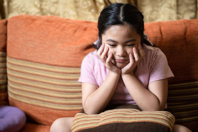 Full length of woman sitting on sofa at home