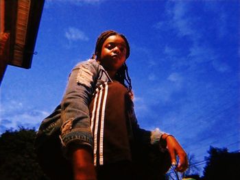 Low angle view of smiling woman against blue sky