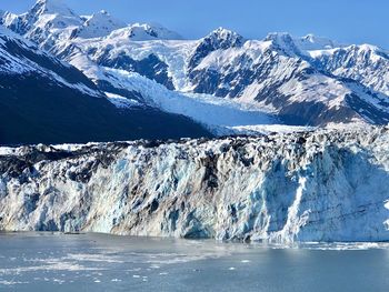 Scenic view of snowcapped mountains by sea against sky