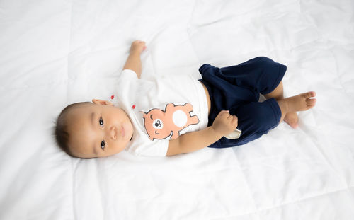 High angle portrait of cute baby lying on bed at home