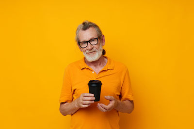 Young woman using mobile phone against yellow background