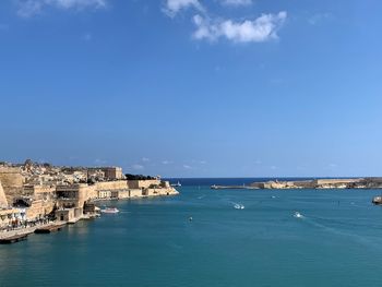 Buildings by sea against blue sky