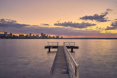 Pier over sea against sky during sunset