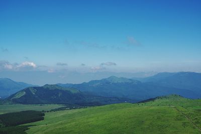 Scenic view of landscape and mountains against blue sky