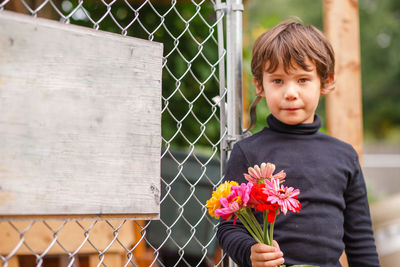 Portrait of boy standing by fence