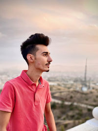 Portrait of young man looking away against sky