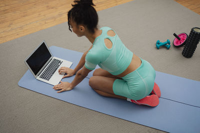 Young woman using laptop while sitting on table