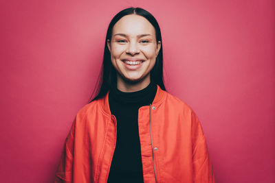 Portrait of smiling young woman against red background