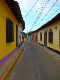 Empty road amidst buildings against sky in city