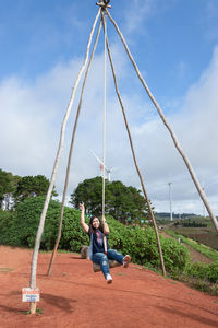 Woman on swing at playground against sky