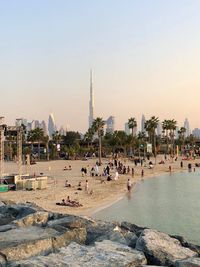 Group of people enjoying at beach against buildings