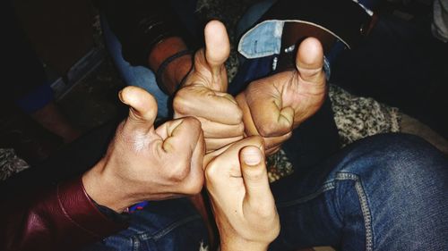 Cropped image of friends showing thumbs up sign