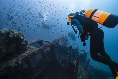 Men and woman scuba diving and examining sunken ship el naranjito undersea