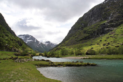 Scenic view of river and mountains against cloudy sky