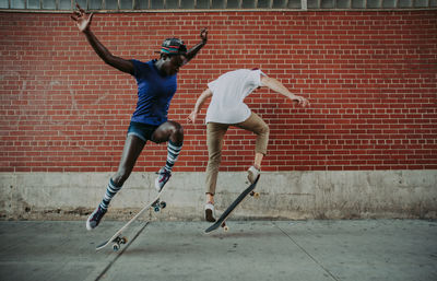 Full length of man jumping against brick wall