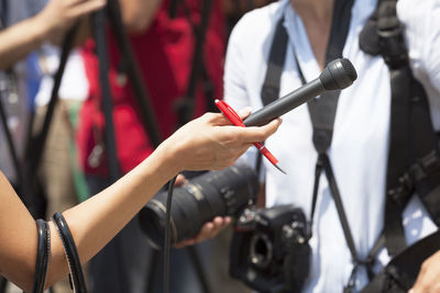 Cropped hand of journalist holding microphone and pen