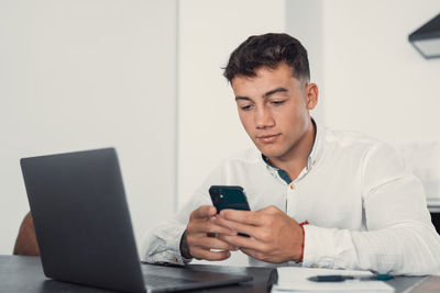 Young man using mobile phone while sitting on table