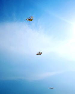 Low angle view of kites flying against sky