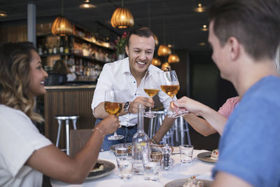 Happy colleagues raising toast during business lunch at restaurant