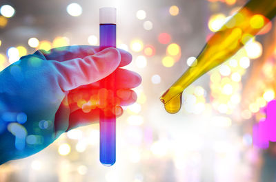 Cropped hand of scientist examining blue chemical in laboratory