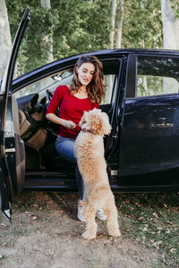 Woman playing with dog while sitting in car at park