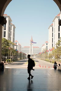 Full length of woman walking by buildings in city against sky