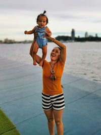 Full length of beautiful young woman in sea against sky