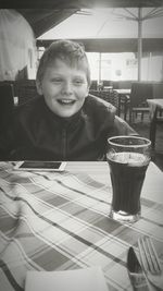 Portrait of smiling boy sitting on table at restaurant