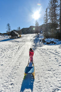 Rear view of child walking on snow during winter