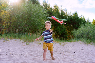 Caucasian little boy launching toy plane into the air