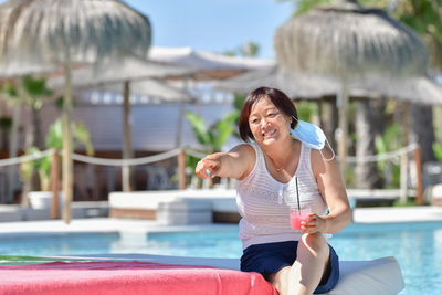 Full length of smiling young woman swimming pool