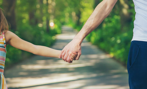 Cropped image of father and daughter holding hands
