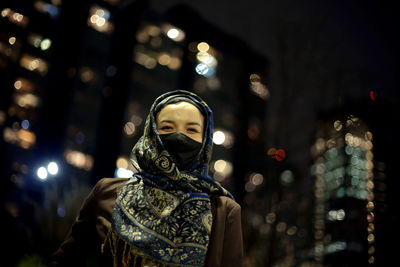 Low angle view of woman wearing hijab against city lights