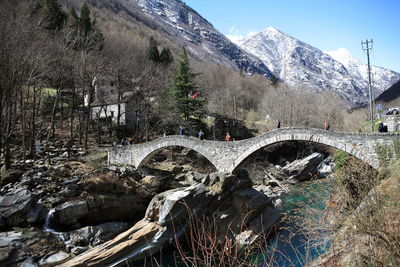 Arch bridge over val verzasca against rocky mountains during sunny day