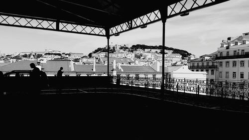 People on bridge over river against buildings in city