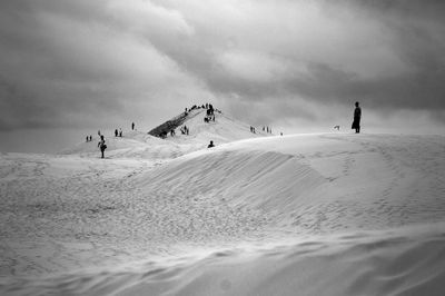 People skiing on snow covered mountain against sky
