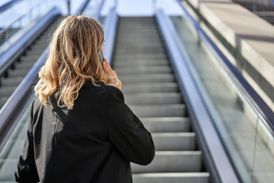 Rear view of woman standing on escalator