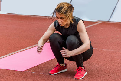 Full length of young woman exercising on sports track