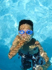 High angle view of shirtless boy holding his breath in swimming pool