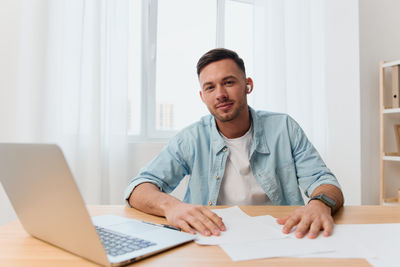 Portrait of businessman using laptop at table